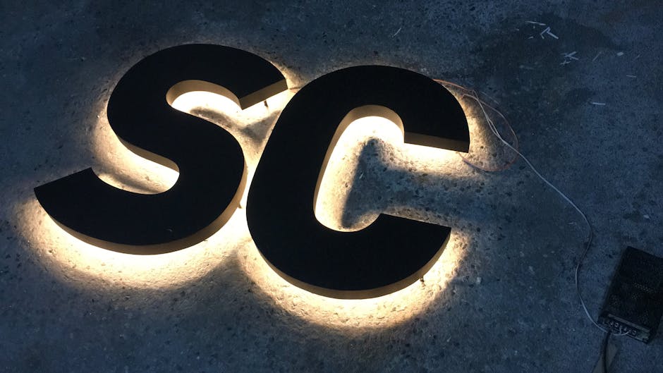 LED backlit 'SC' letters on concrete surface, creating a glowing effect.